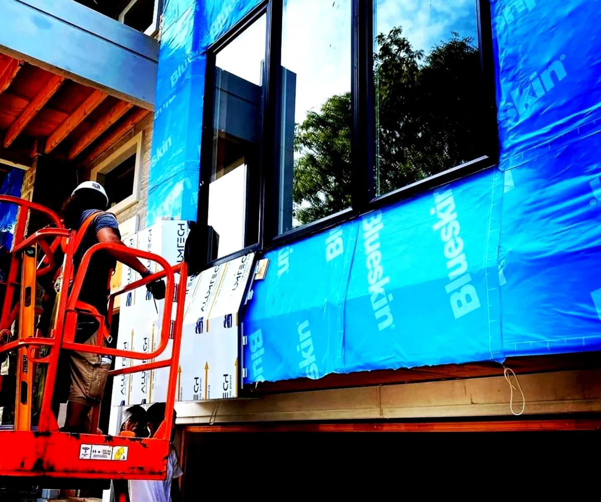 Crew on a lift fitting black metal panels over blue self-adhered membrane