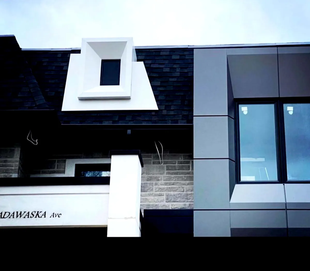 White sculpted dormer above grey metal panels and stone