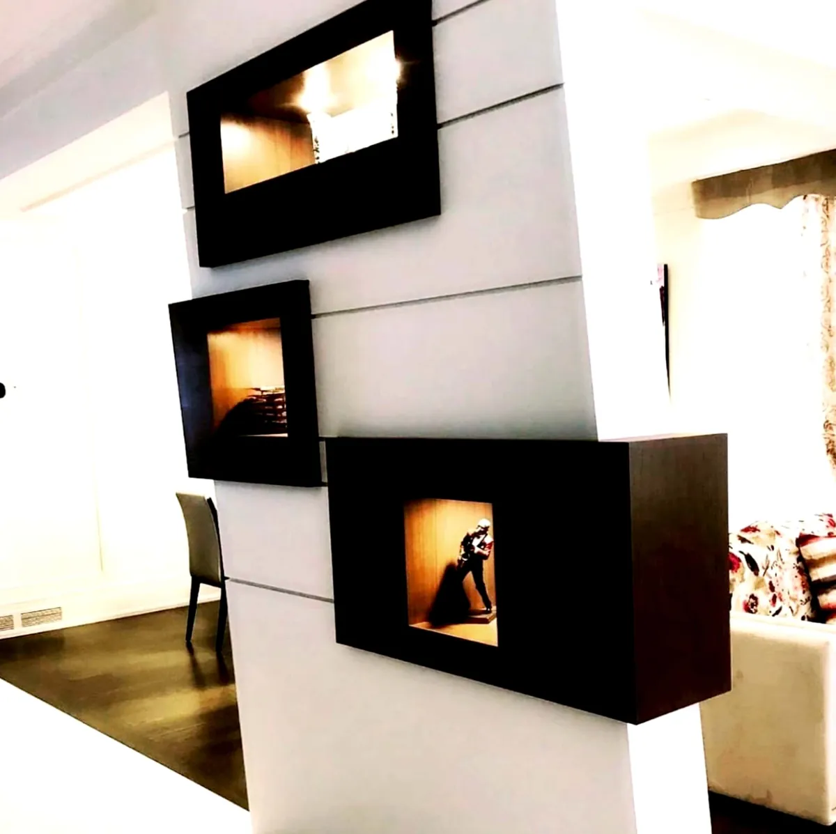 Three dark wood niche boxes with lit alcoves set into a white hallway partition