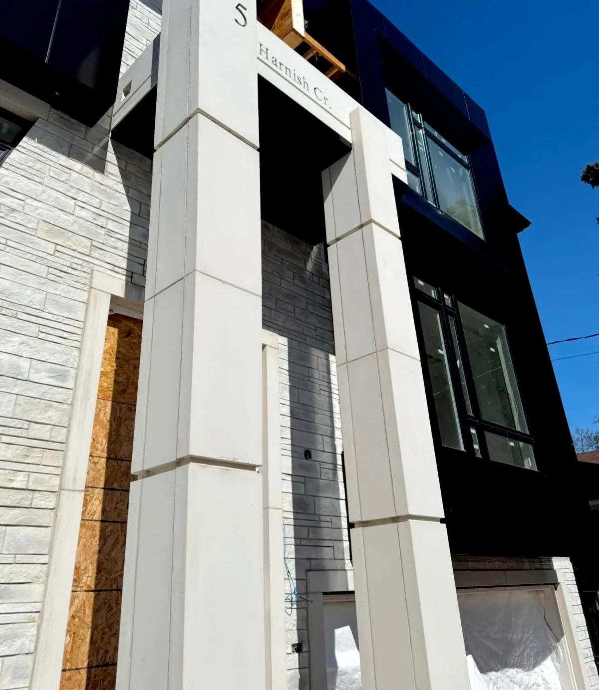 Tall white porch columns beside black cladding and grey stone