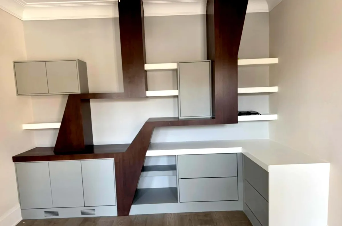 Grey cabinetry with walnut bracket frame and floating white shelves in a study