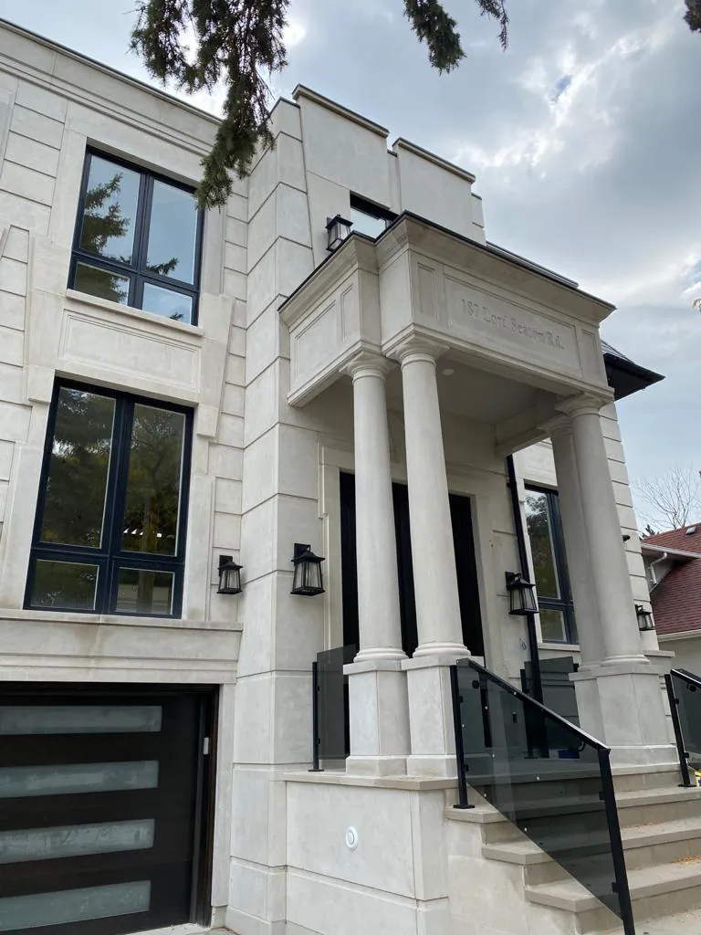 Limestone house with columned portico, glass stair rail and a glazed garage door