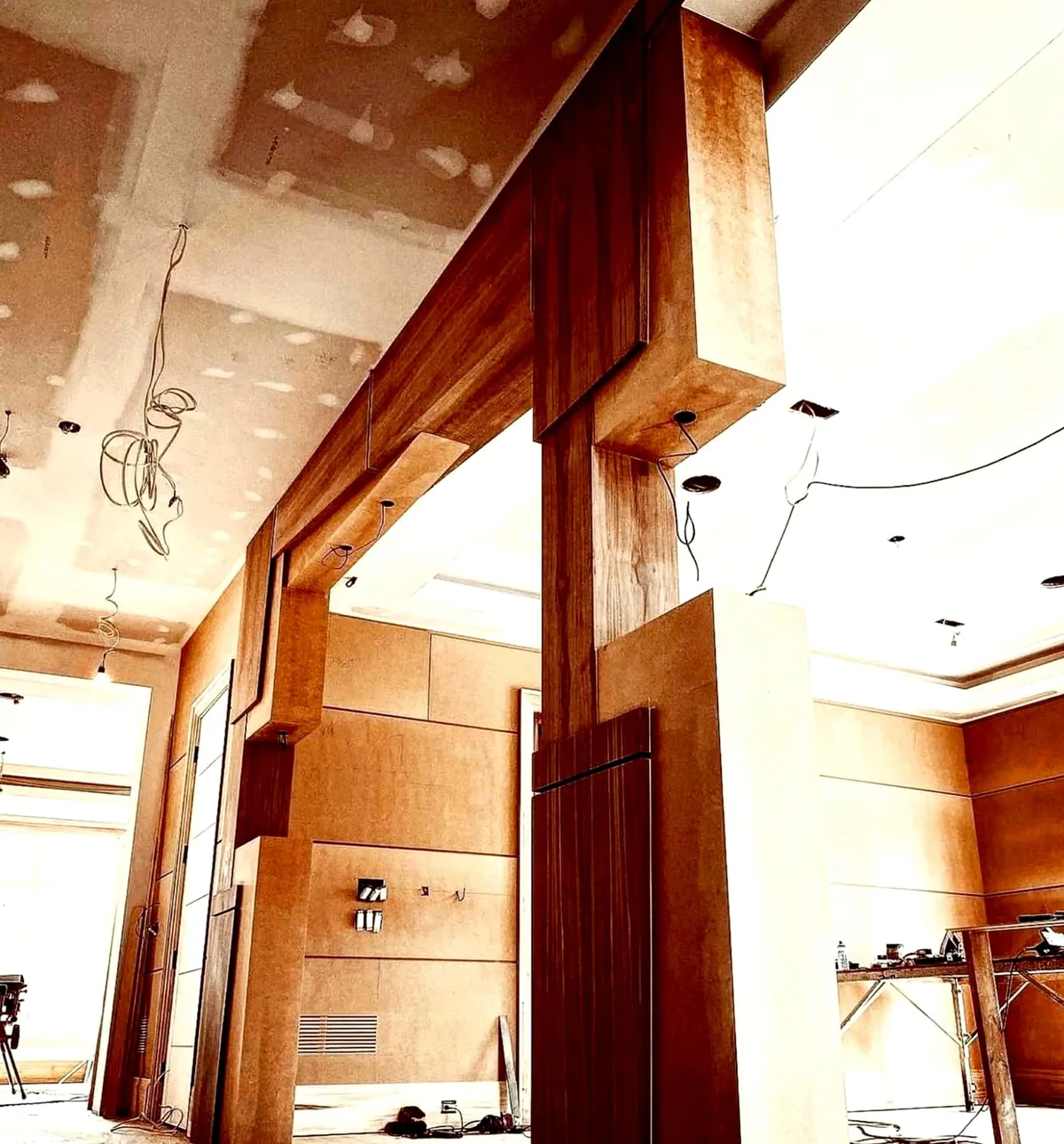 Walnut frame of a ceiling feature standing in an unfinished room with drywall above