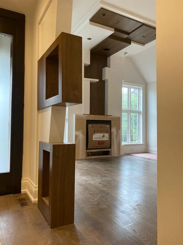Stacked walnut box frames rising from a fireplace to a coffered ceiling feature