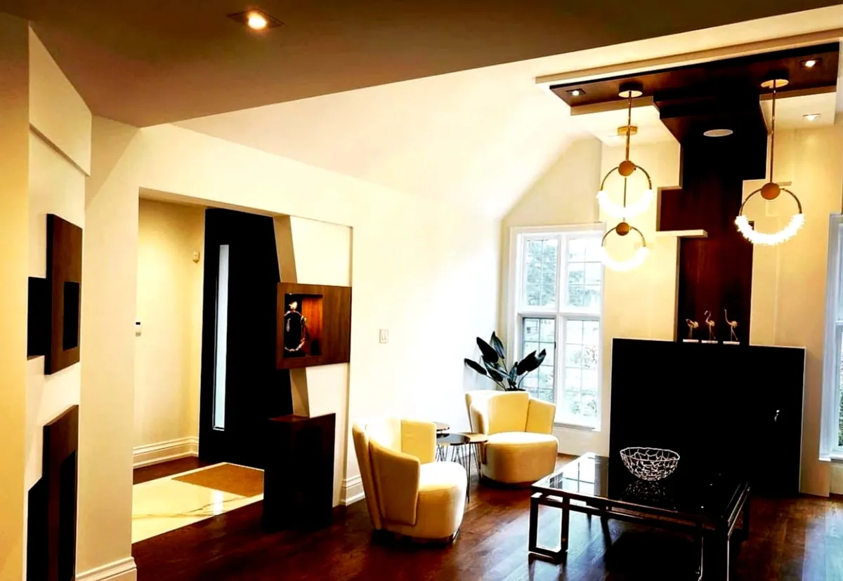 Sitting room with a dark wood feature wall, ring pendants and cream armchairs
