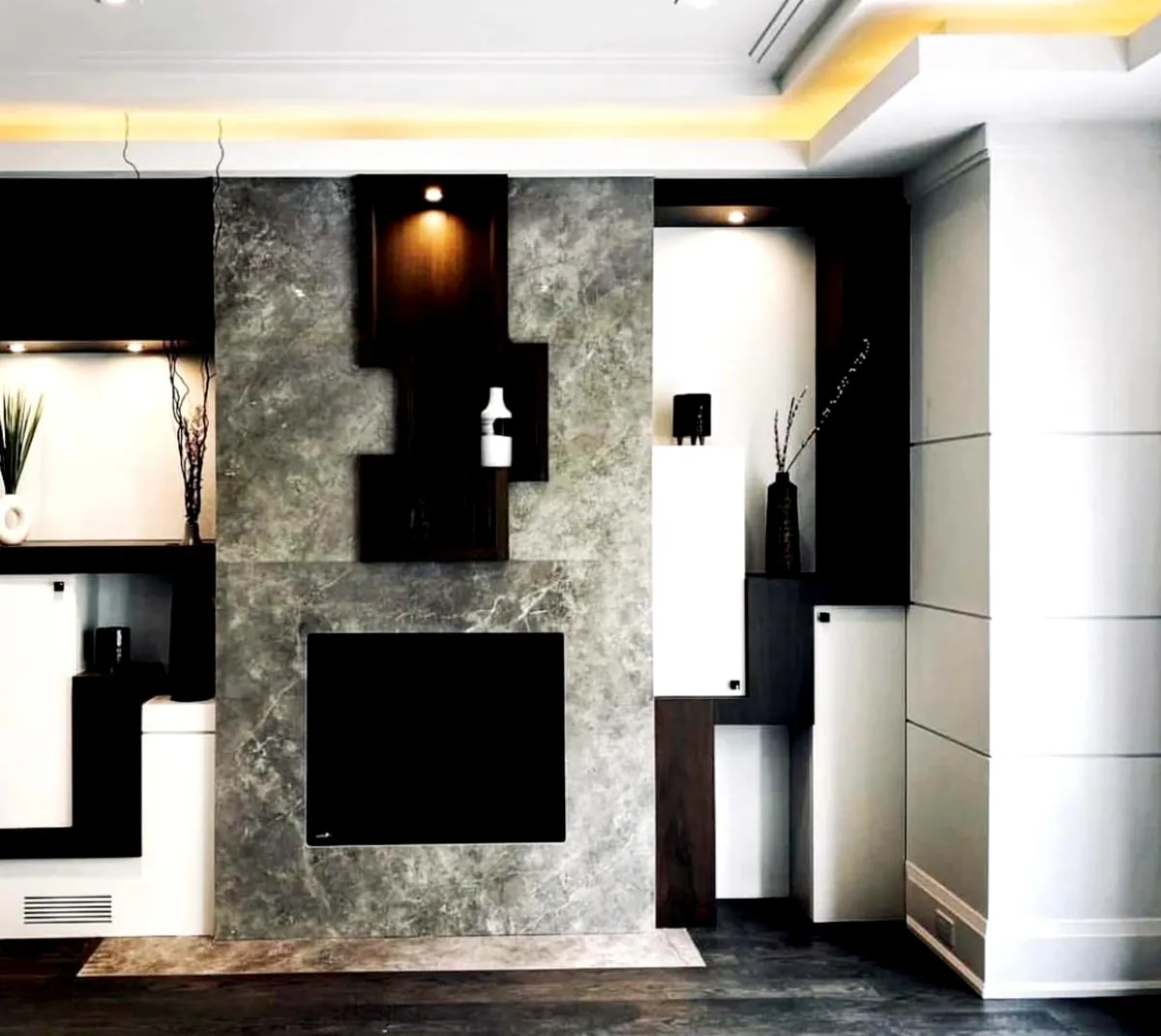 Stone feature wall flanked by black and white boxes with lit niches