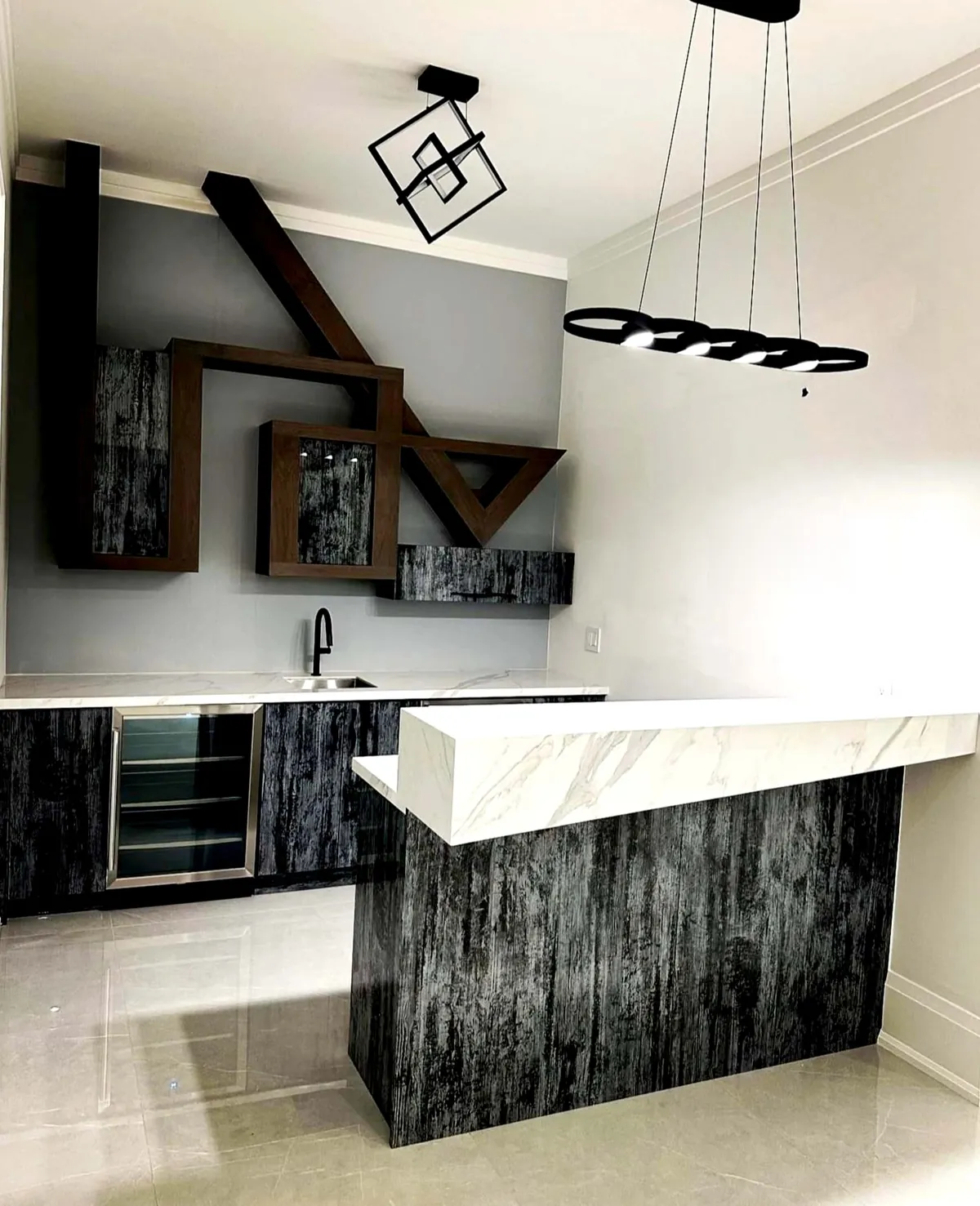 Wet bar with a dark textured base, white stone counter and a sculptural walnut shelf